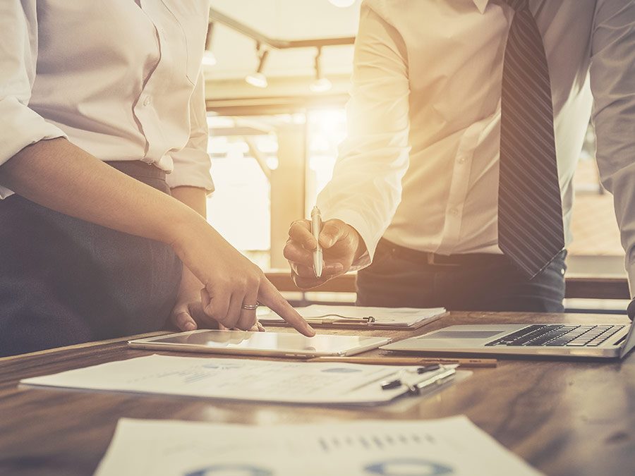 Two accountants discussing paperwork laid out on a desk.