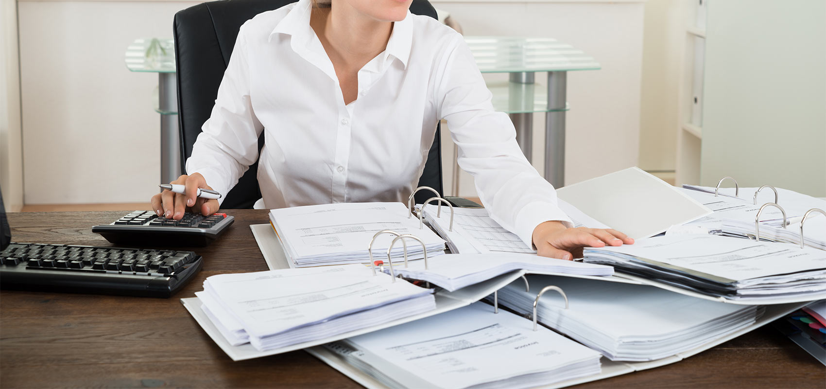 A female accountant reviews documentation on a desk.